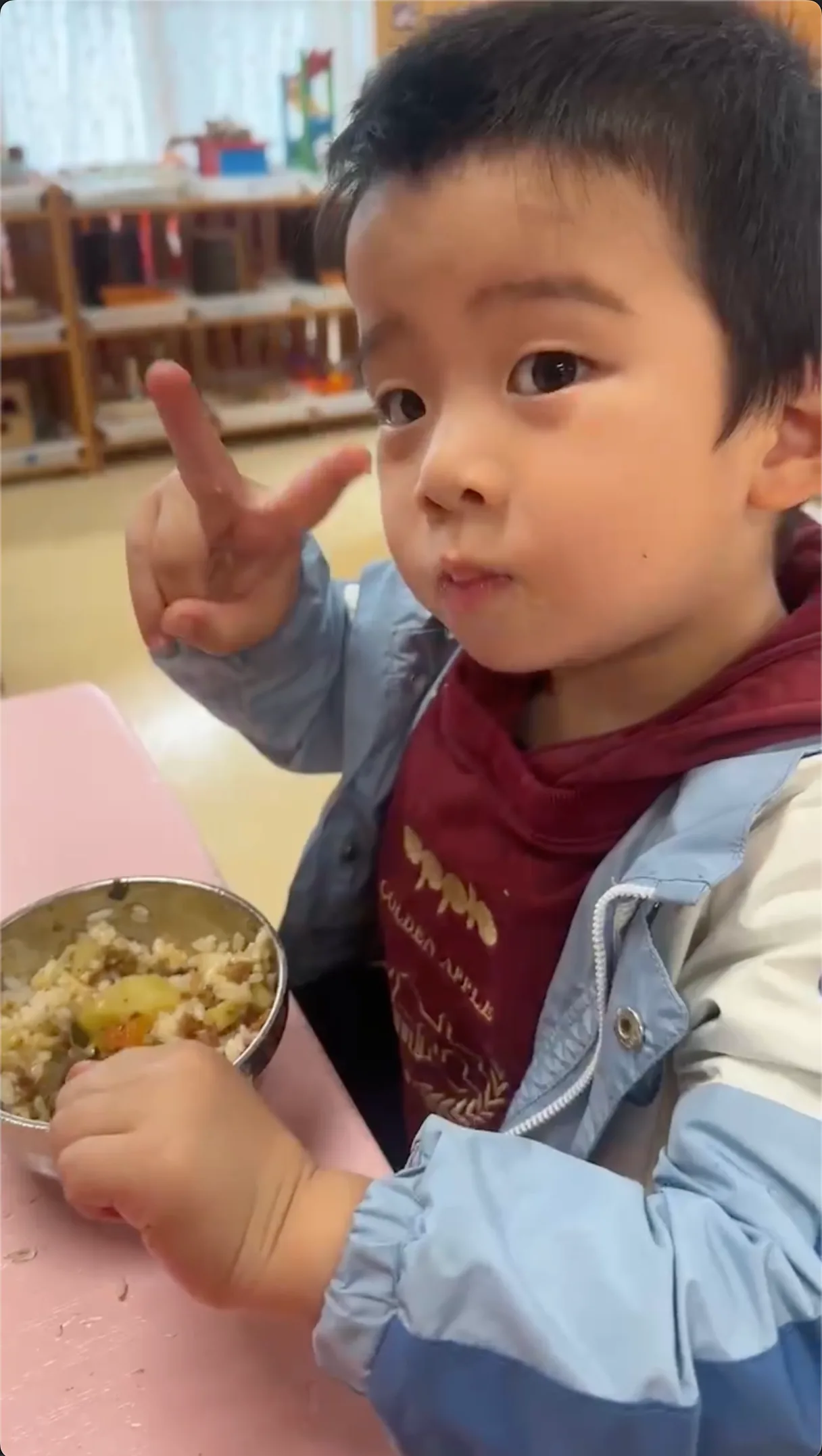 派派在幼儿园认真吃饭并比出胜利手势